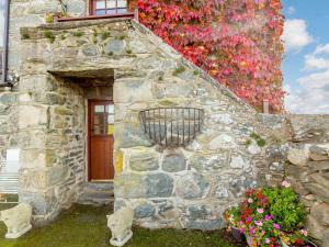 - un bâtiment en pierre avec une porte et des fleurs dans l'établissement 1 Bed in Barmouth 89777, à Dyffryn