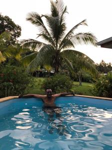 a man in a swimming pool with a palm tree at Maison Nature in Le Moule