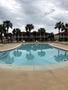 a large blue swimming pool with palm trees in the background at Lazy Palm Panama City Beach Free New 2023 Golf Cart! Across street From Beach! in Panama City Beach