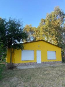 a yellow house with two white doors and a tree at Sin Pensarlo 