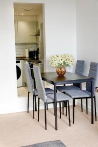einem schwarzen Esstisch mit Stühlen und einer Vase aus Blumen in der Unterkunft Modern Luxurious Apartment in Birmingham