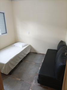 ein kleines Schlafzimmer mit einem Bett und einem Sofa in der Unterkunft Temporada em família e amigos. in Barra do Garças
