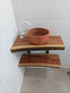 a copper bowl on a wooden shelf in a bathroom at Temporada em família e amigos. in Barra do Garças