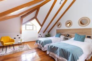 a attic bedroom with two beds and a chair at CASA LALI in La Laguna