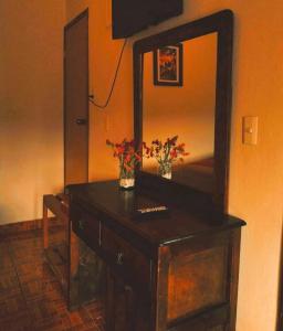un tocador de madera con espejo y flores. en Hotel Posada Dominnycos, en San Cristóbal de Las Casas