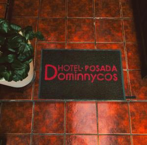 un cartel que dice hotel pago dominoums en un suelo de baldosa en Hotel Posada Dominnycos en San Cristóbal de Las Casas