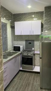 La cuisine est équipée d'une cuisinière, d'un évier et d'un réfrigérateur. dans l'établissement 7th Heaven Homes, à Ibadan