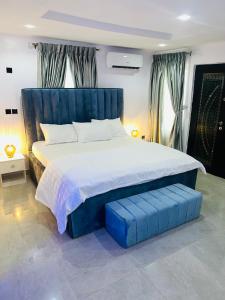 7th Heaven Homes في إيبادان: غرفة نوم مع سرير كبير مع اللوح الأمامي الأزرق