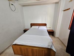 a small bedroom with a bed with white sheets at Hotel El Imperio in Santa Marta