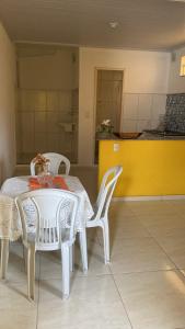 a white table with two chairs and a yellow wall at Kitnet funcional in Angra dos Reis