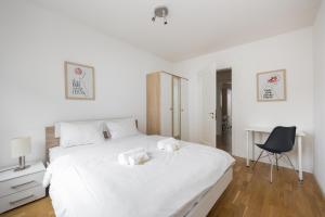 a white bedroom with a large white bed and a chair at Downtown Dream 3,5BR with Balcony and Style BA42 in Zurich