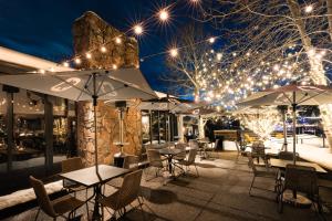 a patio with tables and umbrellas at night at Gravity Haus Steamboat in Steamboat Springs