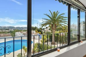 een balkon met uitzicht op een zwembad en palmboom bij Casa Nico- by Aldertons in Teulada