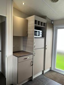 una pequeña cocina con nevera y microondas en WillowWay168, Tranquility Family Home en Camber