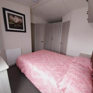 a bedroom with a pink bed with a pink blanket at WillowWay168, Tranquility Family Home in Camber