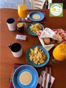 a wooden table with plates of food and orange juice at "Paracas Camp" in Paracas