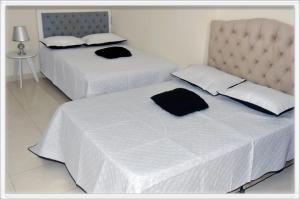 two beds with white sheets and black pillows in a room at Familia angel in Dosquebradas