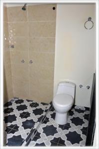 a bathroom with a toilet and a black and white floor at Familia angel in Dosquebradas