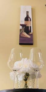 two wine glasses and a vase with flowers on a table at Escarpment Dwelling! in Hamilton