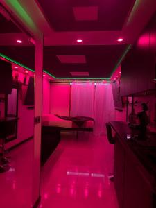 Cette chambre est dotée de lumières roses et d'une table. dans l'établissement 12 Phantasm, au Cap d'Agde