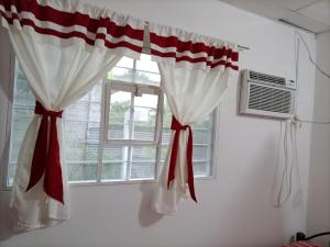 ein Fenster mit roten und weißen Vorhängen in einem Zimmer in der Unterkunft Departamento CUARTITO MODESTO DEL PRECIOSO in Martínez de La Torre