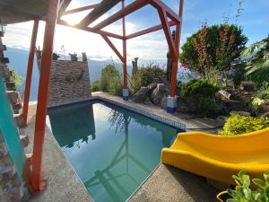 a swimming pool with a yellow slide next to a house at El Domo Macanal in Macanal
