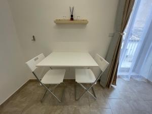 een witte tafel en stoelen in een kamer met een raam bij I Parienti Ra Zita in Ragusa