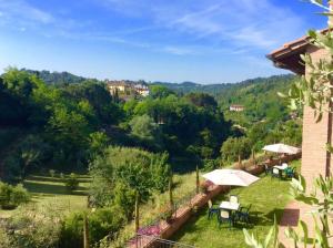 Blick auf einen Garten mit Tischen und Sonnenschirmen in der Unterkunft Casa Vacanze Verdoliva in San Miniato