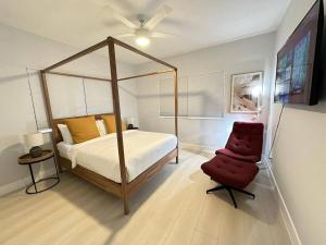 um quarto com uma cama de dossel e uma cadeira vermelha em Cozy 4Bed Home in Calle 8 Miami em Miami