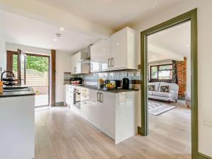 a kitchen with white cabinets and a living room at 2 Bed in Hailsham 89416 in Hailsham