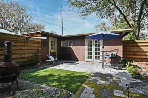 ein Haus mit einer Terrasse mit einem Grill und einem Sonnenschirm in der Unterkunft Quaint Winter Park East End Home in Orlando