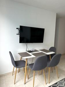 a dining room table with chairs and a tv on a wall at Hermoso Apartamento cerca del centro comercial jardin plaza in Cúcuta