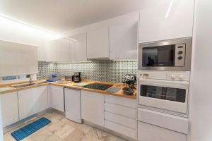 - une cuisine blanche avec des placards blancs et un four micro-ondes dans l'établissement One bedroom house with shared pool terrace and wifi at Canico 1 km away from the beach, à Caniço