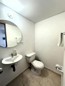 a bathroom with a toilet and a sink and a mirror at Hermoso Apartamento cerca del centro comercial jardin plaza in Cúcuta