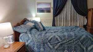 a bedroom with a bed with a blue comforter at Moreland Air Venture Rooms in Oshkosh
