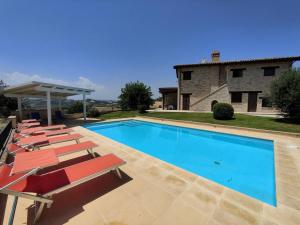 una piscina con sedie a sdraio e una casa di 5 bedrooms house with private pool terrace and wifi at Ripatransone a Cossignano