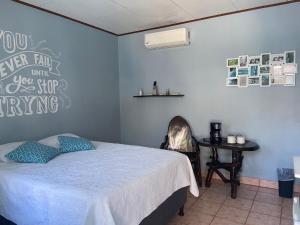 a bedroom with a bed and a desk with a table at Hotel Perico Azul & Surf Camp in Jacó