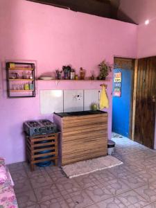 a kitchen with a stove and a pink wall at Studio com varanda in Itacaré