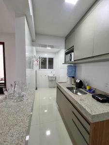 eine weiße Küche mit einem Waschbecken und einer Arbeitsplatte in der Unterkunft Lindo apartamento 1 quarto próximo a Rua de Lazer Domingos Martins in Domingos Martins