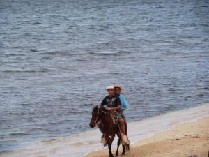 duas pessoas a cavalo na praia em Guanaja Caribbean Cottages em Guanaja