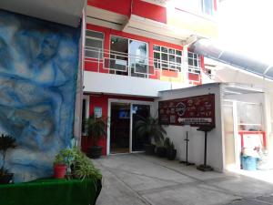 a red and white building with plants in front of it at Hotel Puerto México Aeropuerto in Mexico City