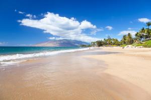 a sandy beach with a mountain in the background at NEW Luxury Condo at Kameole Beach in Wailea