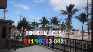 un panneau sur une clôture avec des palmiers en arrière-plan dans l'établissement Recanto Bessa Praia Grande aceito cartão, à Praia Grande