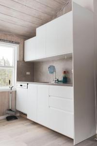 eine weiße Küche mit weißen Schränken und einem Fenster in der Unterkunft Bontveit Villa s in Bergen