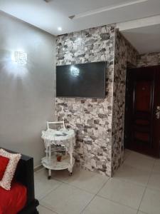 a room with a stone wall with a flat screen tv at Appartement Islane Agadir avec piscine in Agadir