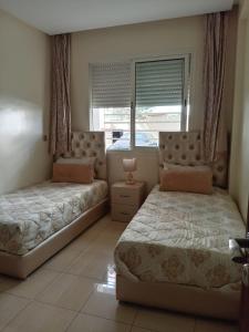 a bedroom with two beds and a window at Appartement Islane Agadir avec piscine in Agadir