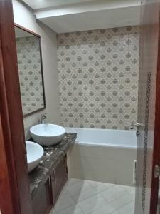 a bathroom with a sink and a tub and a mirror at Appartement Islane Agadir avec piscine in Agadir