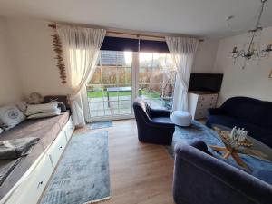 una sala de estar con muebles azules y una gran ventana. en Ferienwohnung Siglinde en Wyk auf Föhr