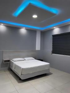 a bedroom with a bed with a blue lighting at Hotel KP in Portoviejo