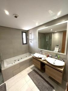 a bathroom with two sinks and a tub and a mirror at Magnifique appartement pleine vue mer Marina Casablanca in Casablanca